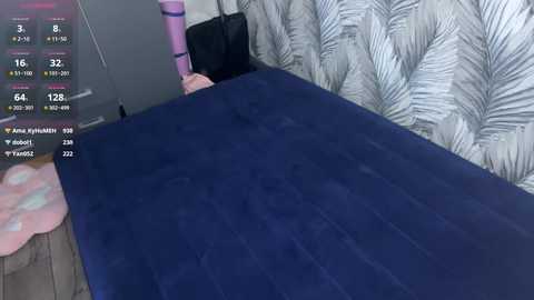 A video showing a person lying on a dark blue velvet bedspread, with a light grey patterned wall and a pink plush toy visible in the background.