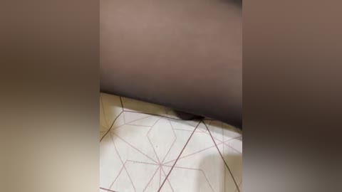 A blurred video shows a close-up of a textured surface with a geometric pattern and a dark smudge. The image has a soft focus, making it difficult to discern details.