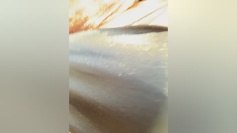 A blurred, close-up video of a woman's face, likely Caucasian, with a smooth complexion, light skin tone, and a slight blush. The background is softly out of focus, suggesting a serene, possibly outdoor setting.