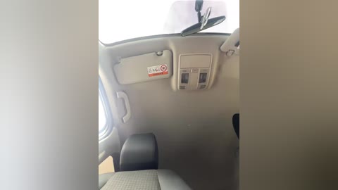 A video of a bus interior, featuring a beige dashboard with a black steering wheel, a \"No Smoking\" sign, and a control panel with a window shade button.