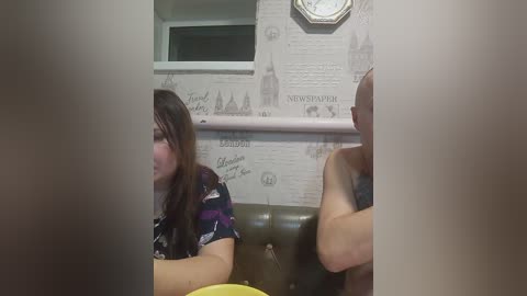 A video captures a young woman with long brown hair, wearing a dark floral shirt, seated on a green leather couch, next to a bald man in a grey shirt. The background features a newspaper-themed wallpaper and a clock.