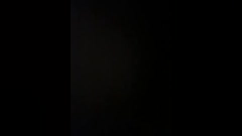 A dimly lit video with a deep black background, showcasing minimal details and a vague, indistinct figure in the center. The image has a moody, mysterious atmosphere, with barely discernible textures and shadows.