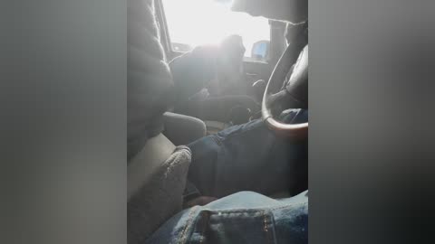Video of a person, likely a woman, reclining in the backseat of a car, wearing a dark sweater and jeans, with sunlight streaming through the window, creating a bright halo effect.
