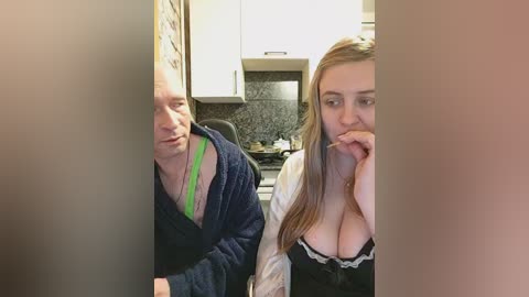 A candid video captures a man in a blue robe, a woman in a revealing black top with lace, both in a kitchen, engaging in oral sex.