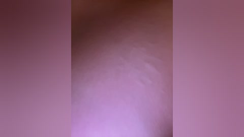 A blurry video showing a person standing in a dark room with soft, pink lighting. The person's silhouette is indistinct, with no discernible features, creating a mysterious and abstract atmosphere.