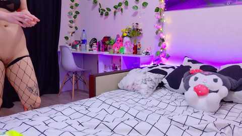 Video of a woman kneeling on a bed with a cow-patterned duvet, wearing fishnet stockings, in a cozy, themed bedroom with cow-themed decor.