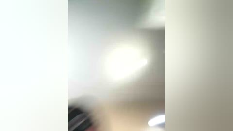 A blurred video shows a person in a dark shirt, possibly female, with a bright light source creating a halo effect. The background is indistinct, suggesting a dimly lit room.