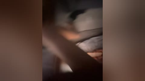 Video of a blurred, intimate moment between two individuals, likely in a dimly lit room. The focus is on a person's arm and hand, partially obscured by shadows, suggesting a close, possibly romantic interaction.