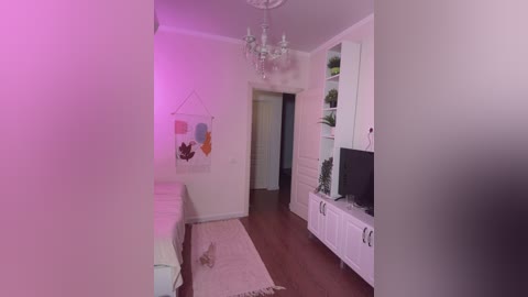 Video of a minimalist, modern living room with white walls, wooden floor, white furniture, a large abstract painting, and a white bookshelf.