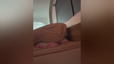 A video of a person sleeping in a small, cozy bed with a brown duvet and pillows, situated inside a vehicle's cabin.