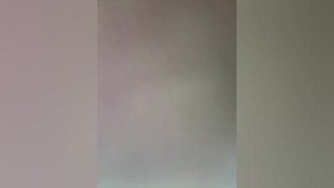 A blurred video of an indistinct person standing against a plain, light-colored wall, with a hint of a shadow suggesting a corner. The background is a soft gradient of muted pastel colors.