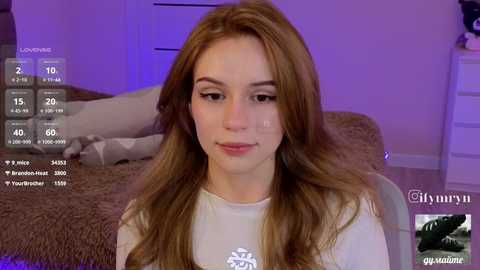 Video of a young woman with long, light brown hair, wearing a white sweater, seated on a beige bed, surrounded by purple lighting and social media icons.