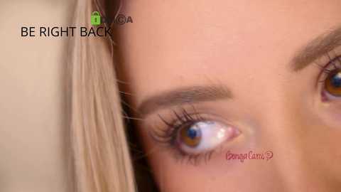 Close-up video of a light-skinned woman with blonde hair, showing her blue-green eye with long lashes, and a small tattoo on her temple. Text overlays read \"BE RIGHT BACK\" and \"Pomme de Terre.\