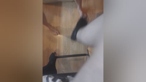 A video showing a blurred, partially clothed woman standing on a wooden floor, holding a white candle, with her hand near her crotch. The background is out of focus.