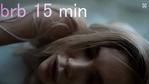A close-up video of a blonde woman with fair skin, wet hair, and a slight smile, lying in a bathtub. Text in the image reads \"brr 15 min.\