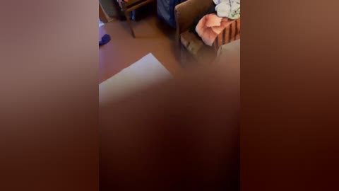 A blurry video of a living room with a brown sofa, a child's toy on the floor, and a white wall in the background.