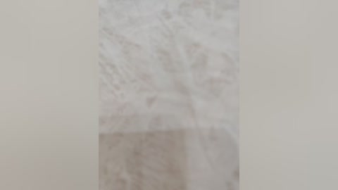 A blurred video of a beige, marble-tiled wall with subtle veining and a slightly reflective surface, suggesting a bathroom or kitchen setting. The image lacks sharpness, making it difficult to discern fine details or textures.