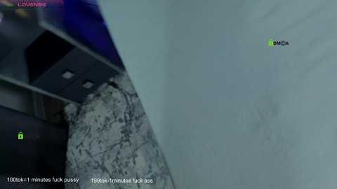 A video capturing a low-angle view of a white wall with a green \"DIMA\" label, showing a surveillance camera recording a marble floor and part of a black office chair.