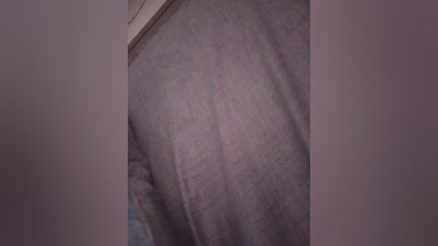 A close-up video of a person's arm and hand wearing a light gray, ribbed, long-sleeve shirt. The image is slightly blurred, focusing primarily on the fabric texture and the contrast between the shirt and the darker background.