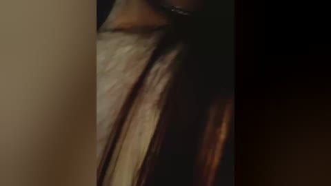 Video of a person's neck, with a dark, blurry background, showcasing smooth skin and a silver necklace. The image emphasizes texture and shadow, highlighting the contours of the neck.