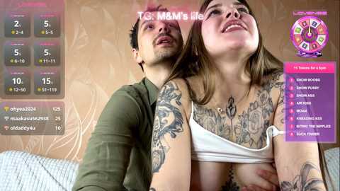 A video shows a tattooed woman in a white bra, leaning forward, with a man behind her, both looking at a digital roulette wheel screen.