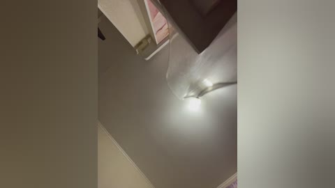 Video of a dimly lit room ceiling with a white fan, beige walls, and a partially visible pink towel hanging on a shelf.