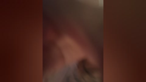 A blurred, dimly lit video featuring a close-up of a person's face, possibly female, with visible lips and skin tone. The background is a warm, reddish-brown hue, contributing to a soft, intimate atmosphere.