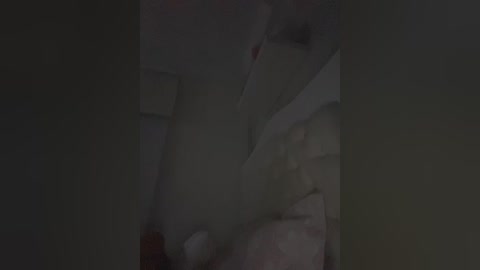 A dimly lit video of a person in a white bathrobe standing in a bathroom, with a towel and a white object, possibly a towel, visible. The image is grainy and dark.