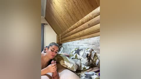 A video of a young woman with light skin and brown hair, lying in a wooden bunk bed, wearing a t-shirt, cuddling a dog, surrounded by a rustic, cozy cabin setting.