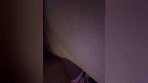 A close-up video of a woman's lower body, focusing on her buttocks and thighs. The skin is light, smooth, and the lighting is dim, creating a soft, shadowy effect.