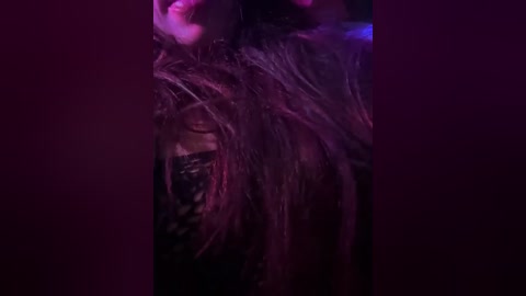 Video of a person with long, wet, dark hair, partially obscured by shadows and dim lighting, creating a dramatic and somewhat mysterious atmosphere.