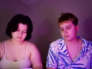 Video of a young, plus-sized woman with short black hair and a beige top, standing next to a short-haired, slim, light-skinned man in a blue floral shirt. They have a serious expression.