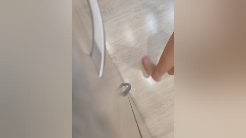 A close-up video of a person's hand opening a white wooden door with a metal handle, revealing a blurred, beige background. The image is slightly out of focus.