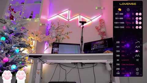 Video of a cozy, lit-up room with a snow-dusted Christmas tree, neon lights, and a white desk with a computer and microphone.