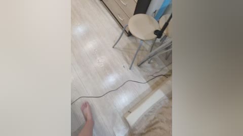 Video of a beige carpeted room with a chair, a table, and a person's hand holding a black wire, capturing a moment of unplugging.