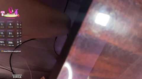 A close-up video of a dark-skinned person's back and arm, with a visible tattoo and a black and white clock showing 5:01 PM. The background is blurred, suggesting an indoor setting.