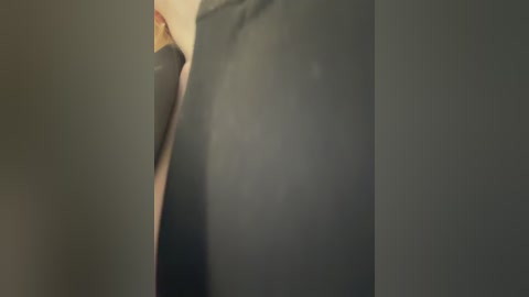 A close-up video of a woman's bare buttocks, captured from a low angle, showing the smooth, slightly dimpled skin texture. The background is blurred and dark, emphasizing the subject.