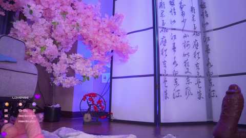 A video of a sensual indoor scene featuring a large, erect penis in the foreground, surrounded by cherry blossom trees, a red lamp, and a Japanese screen with calligraphy. The room is dimly lit with purple hues.