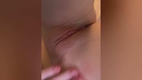 Video of a close-up of a woman's bare breast with a nipple, her hand gently touching her skin, with a warm, soft-focus background.