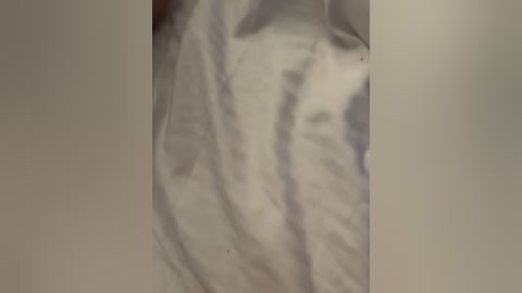 A video of a person's torso, wearing a white shirt with visible wrinkles and folds, partially obscured by a vertical blur, suggesting a close-up, intimate setting.