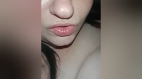 A close-up video of a light-skinned woman's face, focusing on her full lips, slightly parted, and her nose. The background is blurred, with no discernible details.