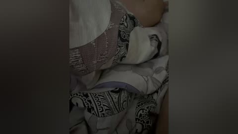 A video captures a close-up of a sleeping woman in a white lace bra and patterned, possibly ethnic, pajamas. She has medium-brown skin and is lying on a bed with a gray and white blanket.