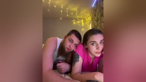 A video of a couple lying on a bed, dimly lit with string lights, the man's arm around the woman, both wearing casual clothes.