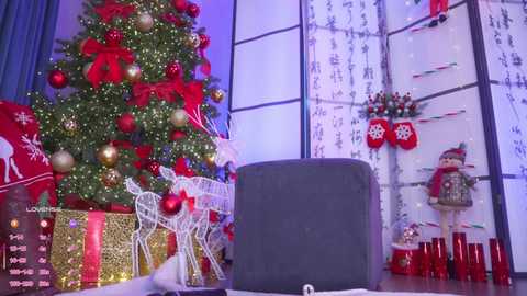 Video of a festive Christmas scene with a decorated tree, gifts wrapped in gold and red, a black hat, and holiday-themed decorations.