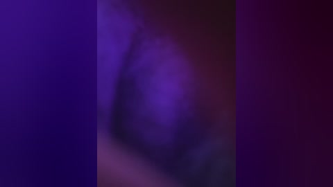 A blurred video with a purple and pink gradient background, featuring a faint, indistinguishable figure, possibly a person, partially obscured by the colors. The image has a dreamy, abstract quality with a soft focus.