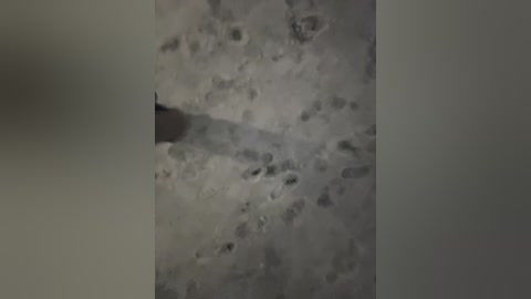 Video of a close-up, textured surface with a shadow cast by an unseen object on the left. The surface appears rough and uneven, with a mix of light and dark tones, suggesting a marble or concrete material.