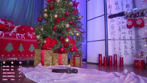 A video of a festive indoor scene with a decorated Christmas tree, wrapped in gold and red paper, surrounded by red and gold ornaments.