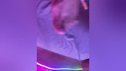 A blurred video with a purple hue, showing a person in a white shirt and red shorts, partially obscured by motion blur. Neon lights create a colorful, vibrant background.