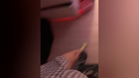 A blurry video of a person wearing a striped shirt, wiping a white surface with a green sponge, surrounded by a red and black background.