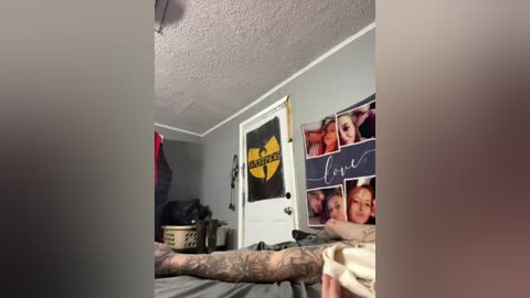 Video of a gray-walled room with a white door featuring a \"Gangsta\" sign and framed family photos. A tattooed arm with intricate designs is seen in the foreground.